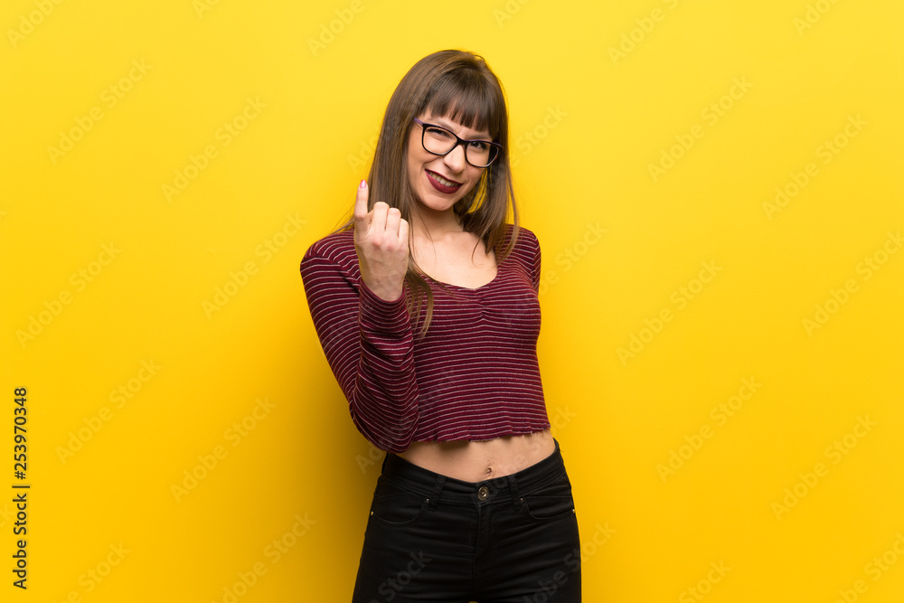Woman with glasses over yellow wall inviting to come with hand. Happy that you came Woman with glasses over yellow wall inviting to come with hand. Happy that you came