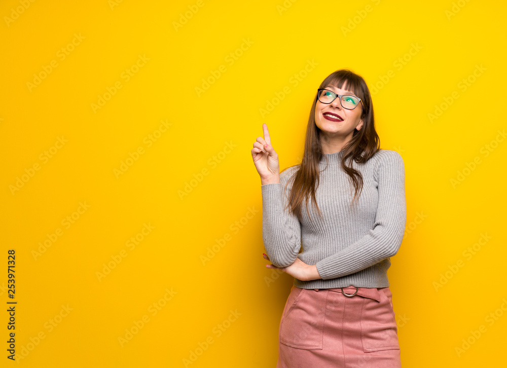 Woman with glasses over yellow wall pointing a great idea and looking up Woman with glasses over yellow wall pointing a great idea and looking up