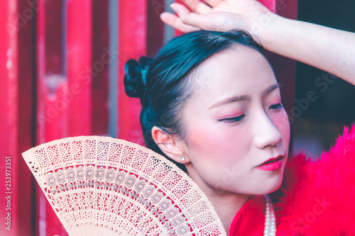 Young chinese woman with Fan on red background for chinese new year concept