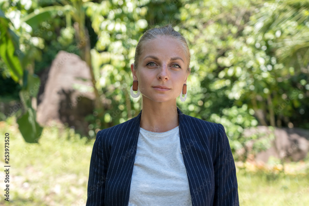 Beautiful caucasian blonde girl in a business suit in nature background. A portrait of a young business woman in tropical garden, Thailand Beautiful caucasian blonde girl in a business suit in nature background. A portrait of a young business woman in tropical garden, Thailand