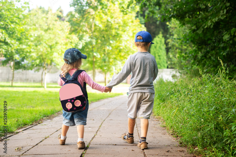 Children's friendship. Children walk in park and hold hands