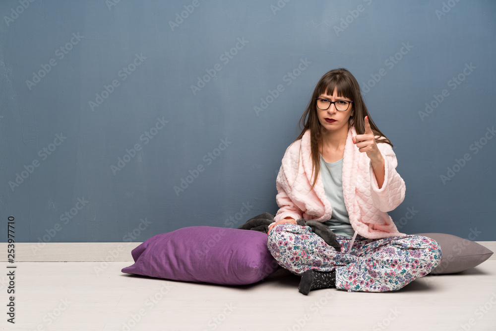 Woman in pajamas on the floor frustrated and pointing to the front Woman in pajamas on the floor frustrated and pointing to the front