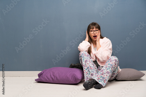 Woman in pajamas on the floor with surprise and shocked facial expression © luismolinero
