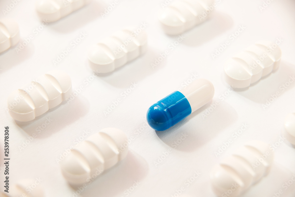 many white pills a blue one on white background many white pills a blue one on white background