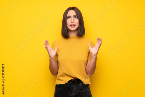 Young woman over yellow wall frustrated by a bad situation