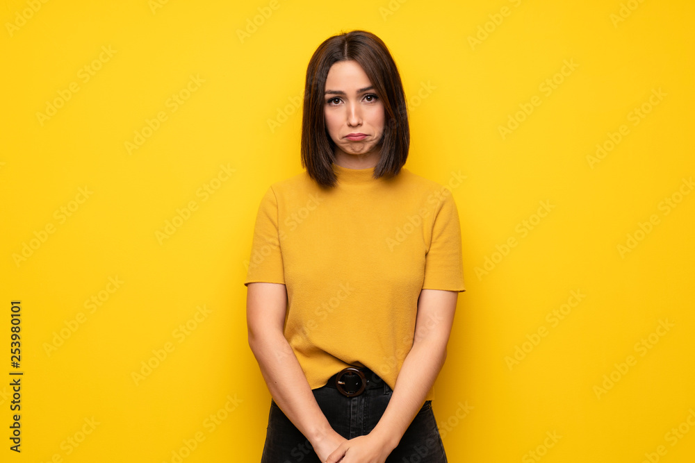 © luismolinero - Young woman over yellow wall with sad and depressed expression