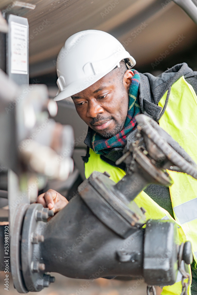 AfroAmerican train mechanic wearing safety equipment (helmet and