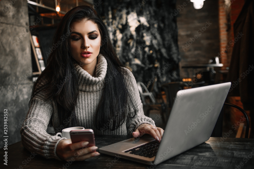 Business woman working on a laptop and drinking coffee in a cafe.