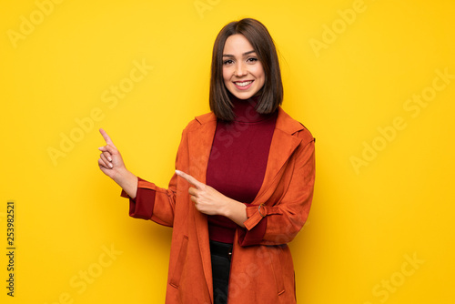 Young woman with coat pointing finger to the side © luismolinero