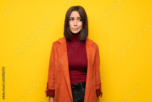Young woman with coat with confuse face expression while bites lip © luismolinero