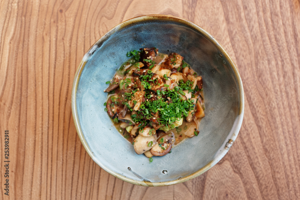 Teppanyaki mushrooms with green leek in earthenware bowl Teppanyaki mushrooms with green leek in earthenware bowl