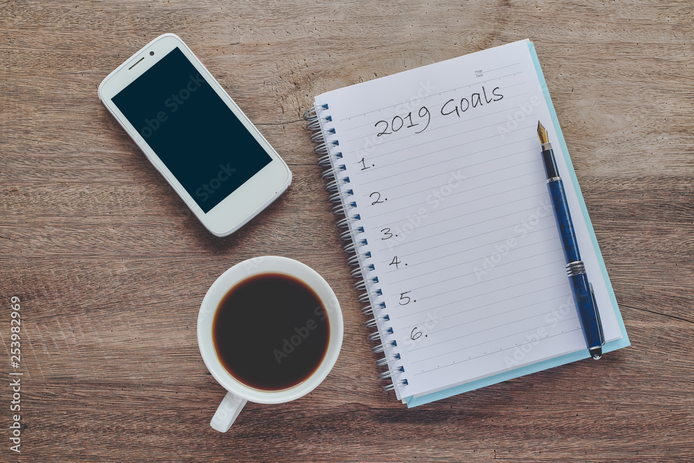 2019 goals text on book note with cup of coffee, pen and smartphone. 2019 goals text on book note with cup of coffee, pen and smartphone.