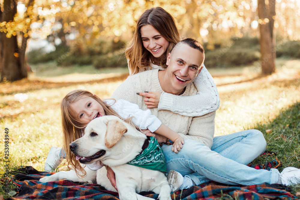 Happy beautiful family with dog labrador is having fun are sitting on green grass in park. Happy beautiful family with dog labrador is having fun are sitting on green grass in park.
