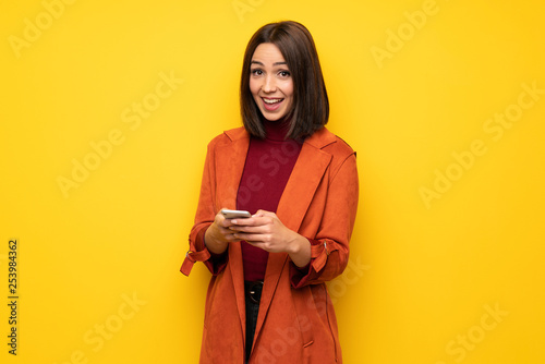 Young woman with coat surprised and sending a message © luismolinero
