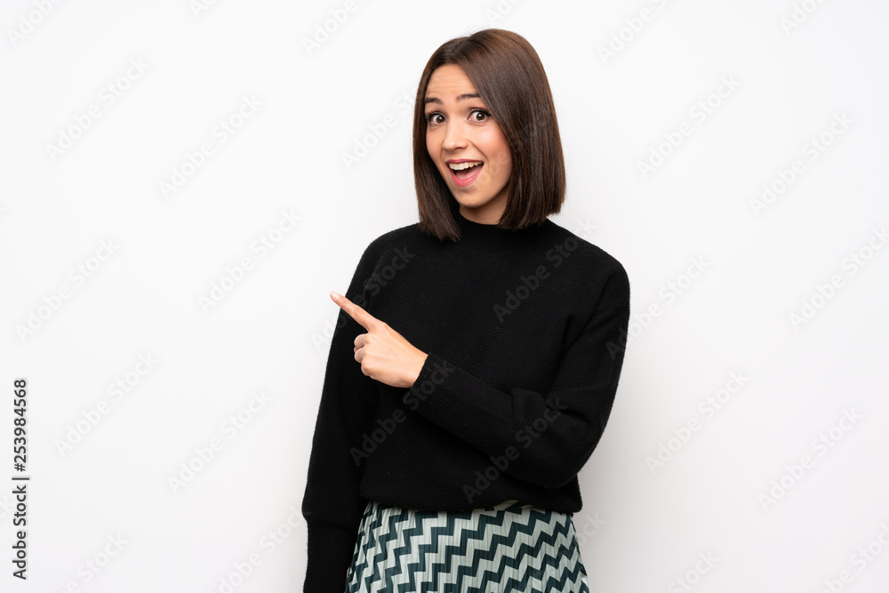 Young woman over white wall surprised and pointing finger to the side Young woman over white wall surprised and pointing finger to the side