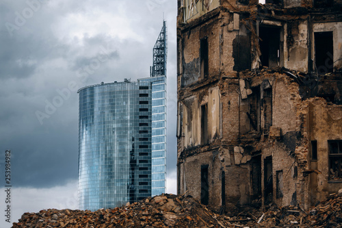 A new modern glass skyscraper and a destroyed old building. photo