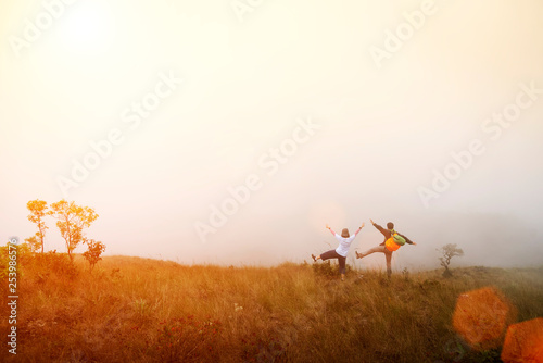Happiness travelers standing on mountain with sunrise or sunset and flare. Travel and vacation concept.