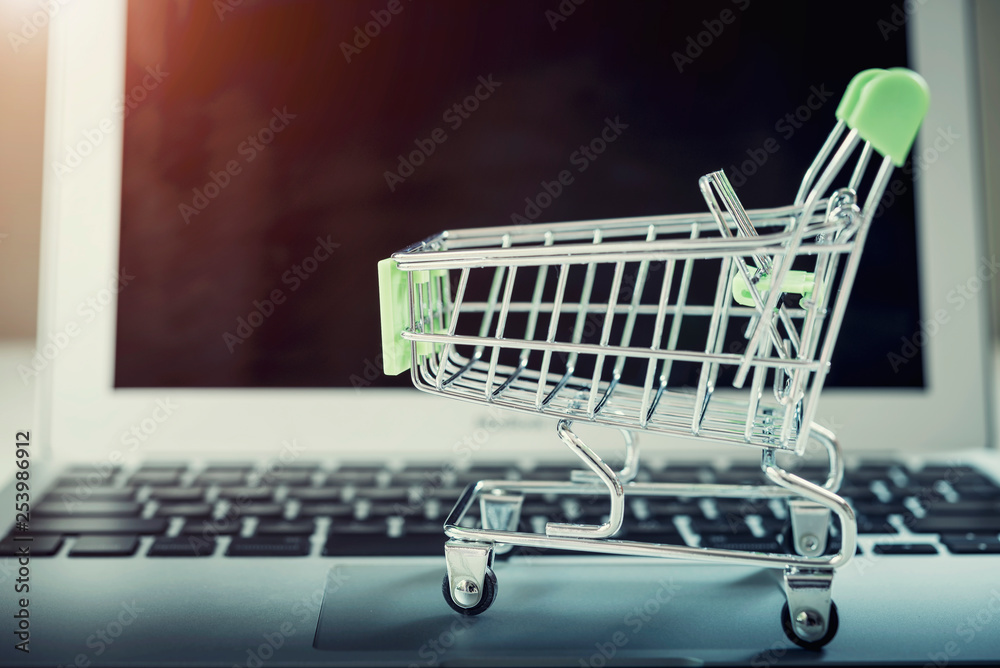 Shopping basket on top of laptop with free copy space. Online shopping and payment concept. E-commerce and global network business. Shopping basket on top of laptop with free copy space. Online shopping and payment concept. E-commerce and global network business.