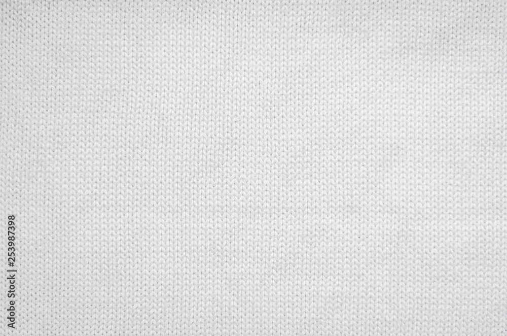 White knitted fabric background. The texture of the white wool fabric. White knitted fabric background. The texture of the white wool fabric.
