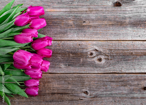 Bouquet of pink tulips on a wooden plank table.