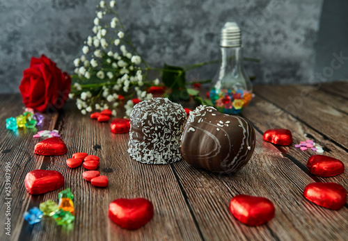 Romantic still life, red rose, chocolate in the shape of hearts and the inscription love on a wooden background. Valentine's day concept. Soft focus
