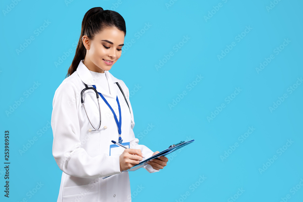 Portrait of bright young woman doctor with stethoscope and clipboard over blue background. Portrait of bright young woman doctor with stethoscope and clipboard over blue background.