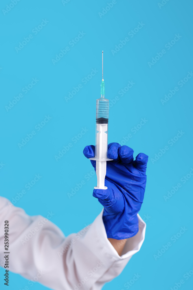 Close up photo of young doctor hand in gloves holding syringe over blue background. Close up photo of young doctor hand in gloves holding syringe over blue background.