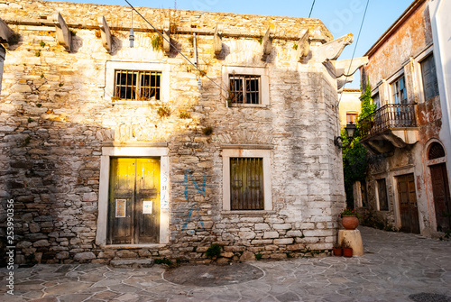 Fototapeta Naklejka Na Ścianę i Meble -  An old house and an alley bathed in sunlight in Greece