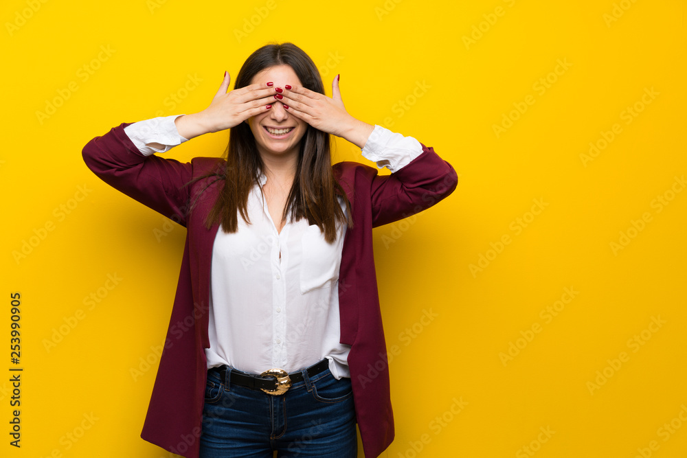 Young woman over yellow wall covering eyes by hands. Surprised to see what is ahead Young woman over yellow wall covering eyes by hands. Surprised to see what is ahead