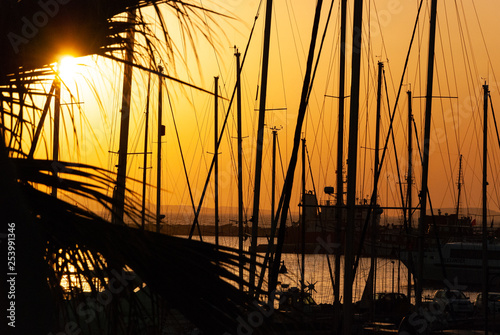 Sail boats in the ocean, the blue sky and the golden sun during sunset in the background - back light