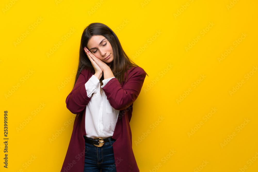Young woman over yellow wall making sleep gesture in dorable expression Young woman over yellow wall making sleep gesture in dorable expression