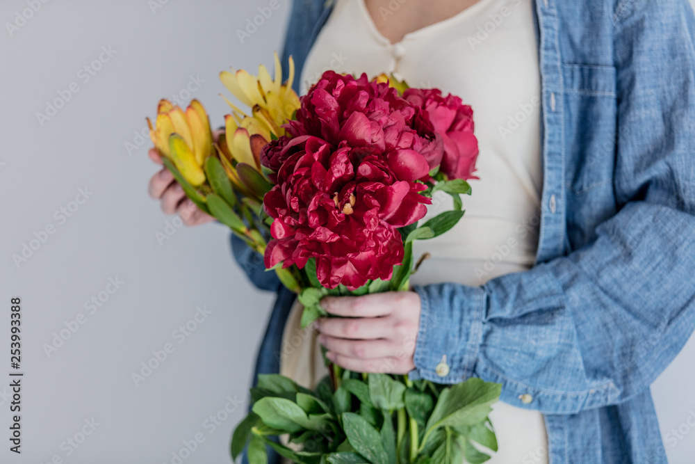 Female hands holding bouquet of peonies and Leucadendron Female hands holding bouquet of peonies and Leucadendron