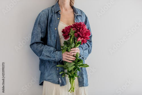 Female hands holding bouquet of peonies on white background