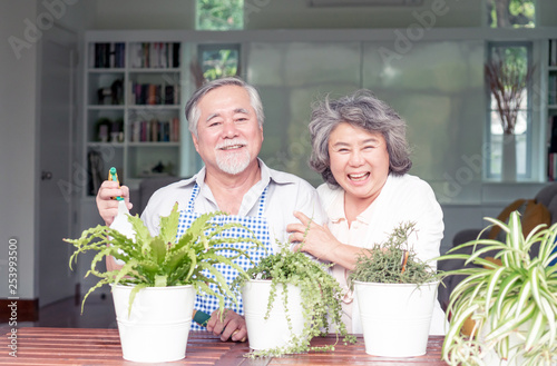 Asian senior couple smile watering plants take care of trees , happy couple gardening - lifestyle senior concept © suphaporn