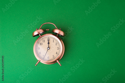 Bronze vintage alarm clock on green table background photo