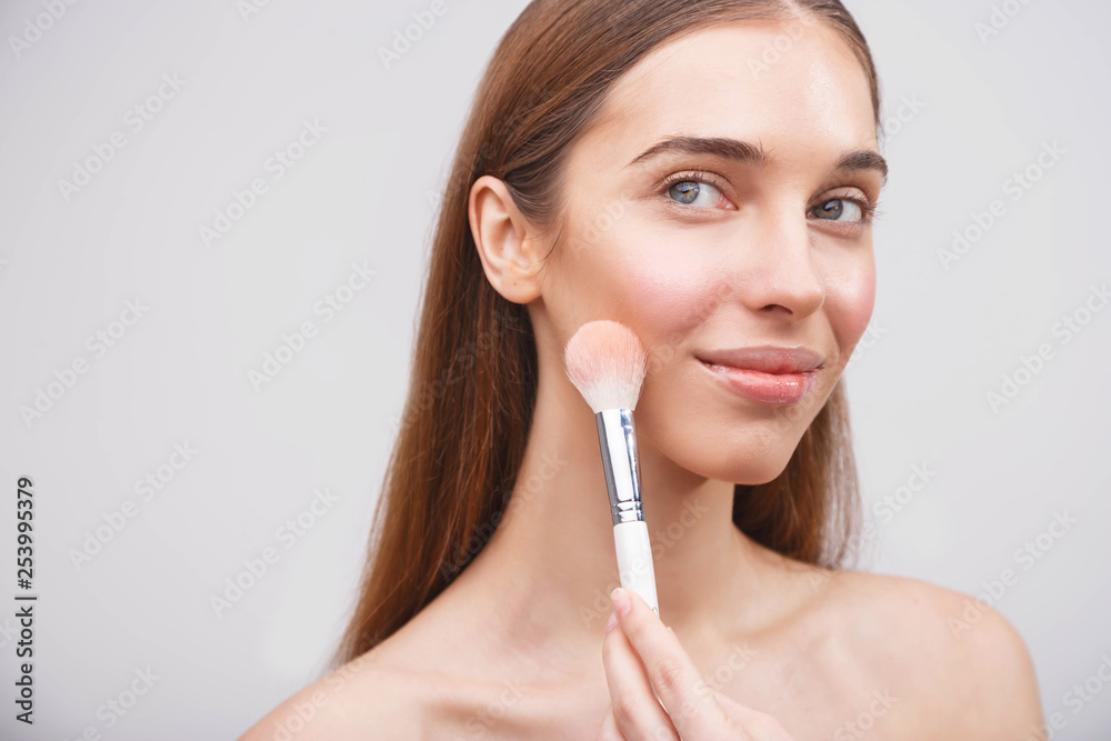Portrait of a girl applying blusher on her skin Portrait of a girl applying blusher on her skin