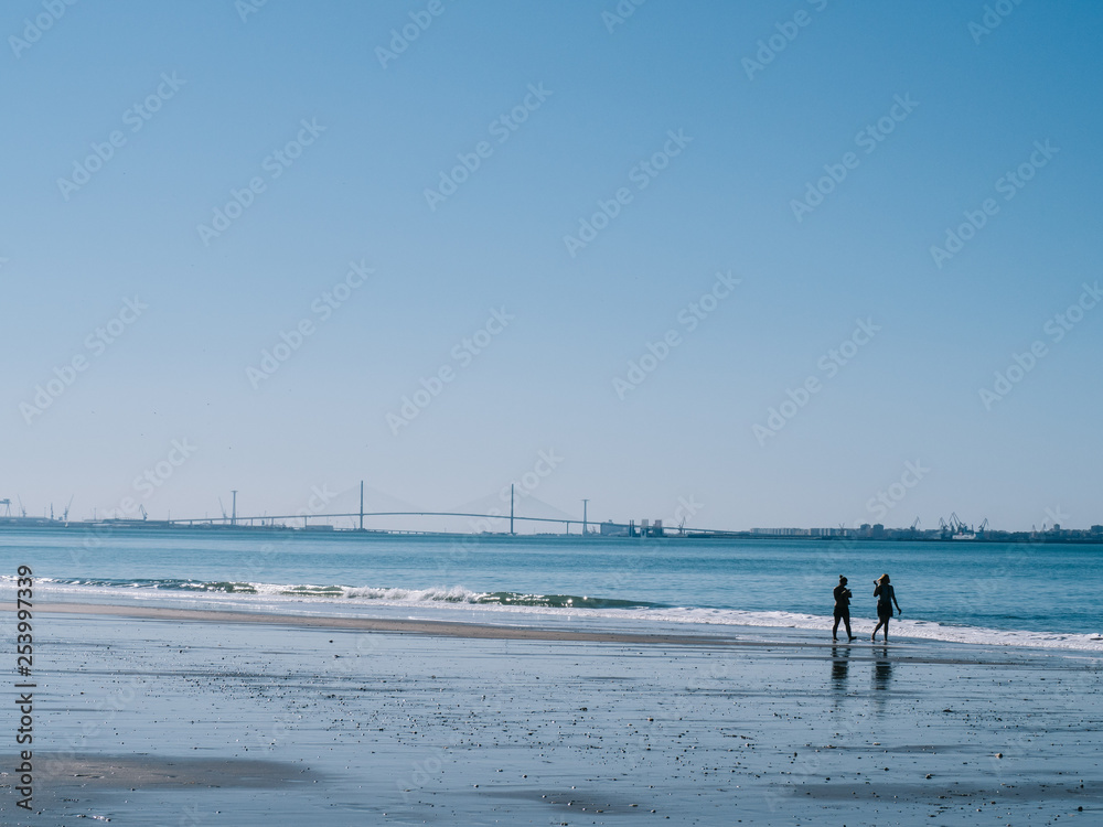 People walking along the shore of the beach