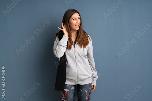 Young sport woman listening to something by putting hand on the ear