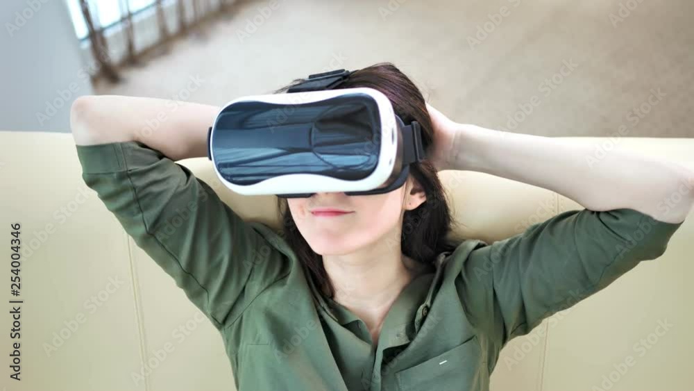High angle portrait of smiling young woman putting on modern virtual reality glasses High angle portrait of smiling young woman putting on modern virtual reality glasses
