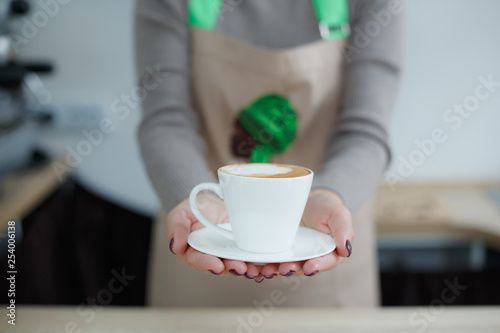 Barista in apron in coffee shop give just brewed fresh coffee to customer