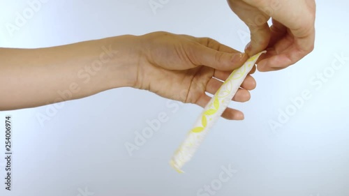 Female hands opening a tampon package with plastic applicator