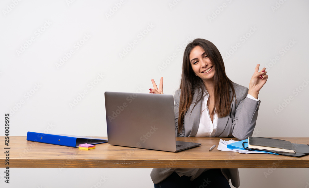Business woman in a office smiling and showing victory sign with both hands Business woman in a office smiling and showing victory sign with both hands