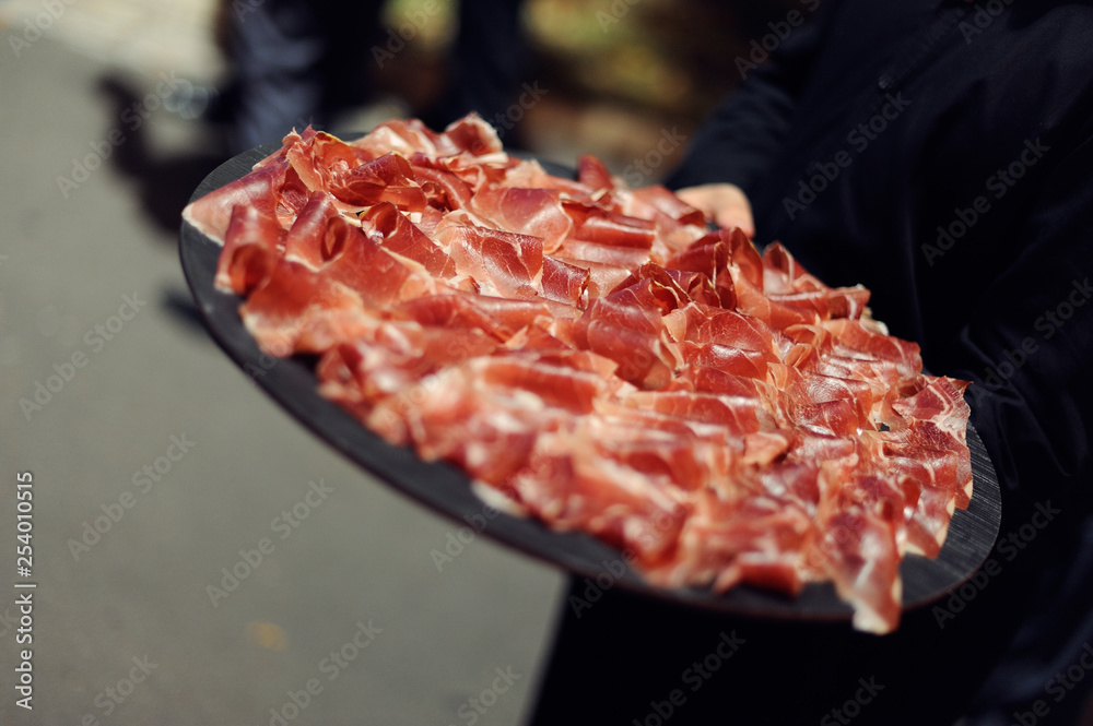 Jamón de bellota presentado en plato sujeto por camarero Jamón de bellota presentado en plato sujeto por camarero