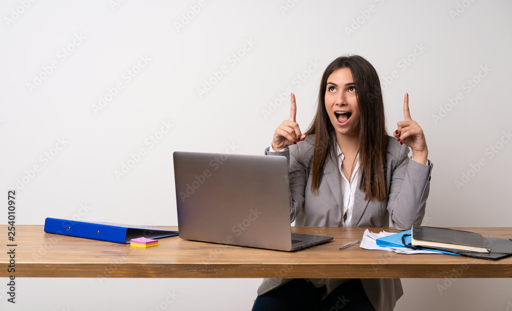 Business woman in a office surprised and pointing up Business woman in a office surprised and pointing up