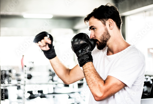 Portrait handsome man practicing boxing on a punching bag at gym