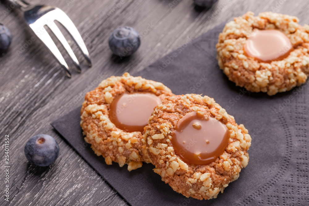 Peanut shortbread cookies with caramel jam inside on a black napkin with blueberries and a patterned dessert fork. Peanut shortbread cookies with caramel jam inside on a black napkin with blueberries and a patterned dessert fork.