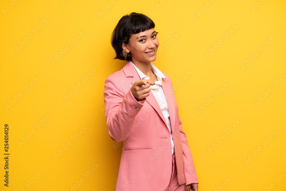 Modern woman with pink business suit points finger at you with a confident expression Modern woman with pink business suit points finger at you with a confident expression