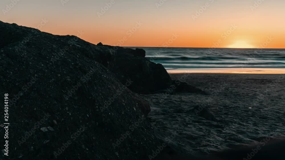 Golden light leak from sunset. Day to night view across dune section of Venice beach with fast motion people crossing through scene during golden hour. Golden light leak from sunset. Day to night view across dune section of Venice beach with fast motion people crossing through scene during golden hour.