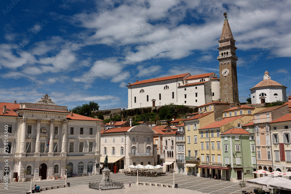 Sunny Tartini Square in Piran Slovenia with government building, statue, St. George's Parish Church with belfry and baptistry