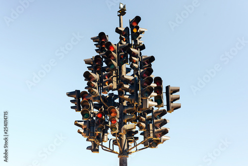 Traffic light tree with lots of lamps under the sky.